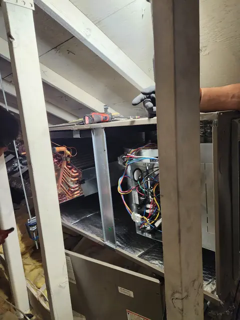 An evaporator coil and wiring inside a cabinet in a tight attic