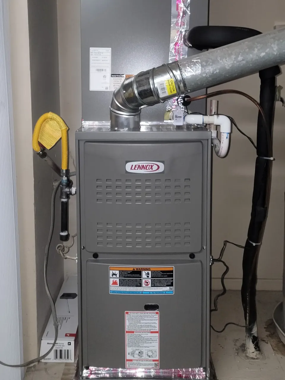 A furnace installed in an alcove, with its vent pipe and a flexible duct above it