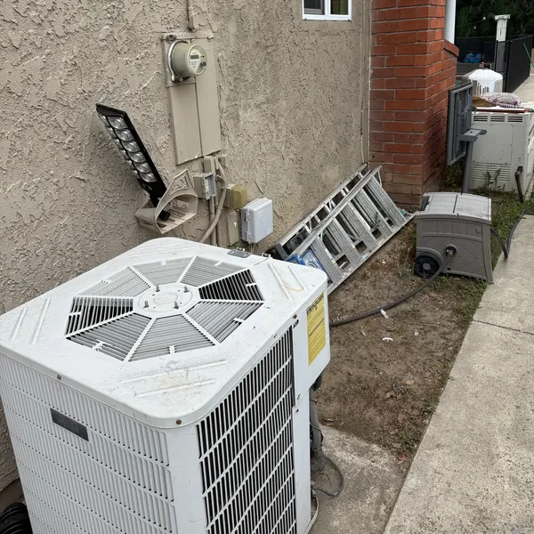 A split system's outdoor unit beside a house, with a ladder against the wall