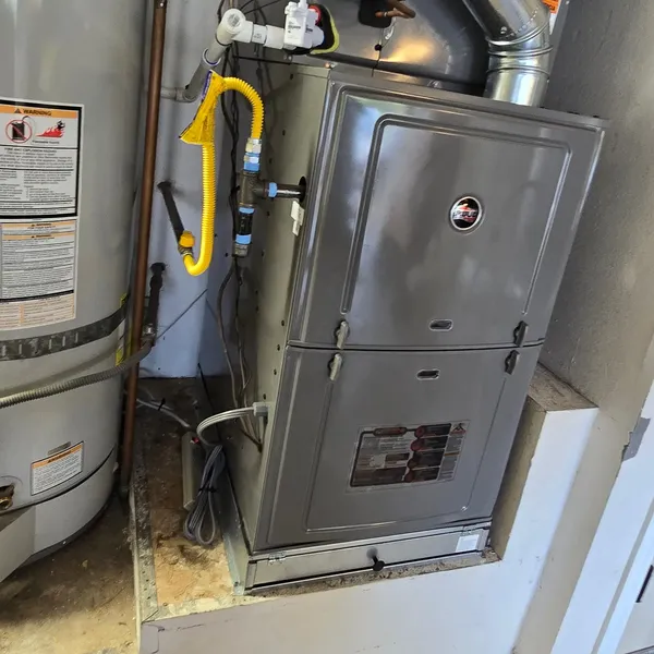 A gas furnace with its vent pipe beside a water heater